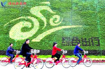 市民騎公共自行車路過市人民廣場一處花壇。記者 張馳